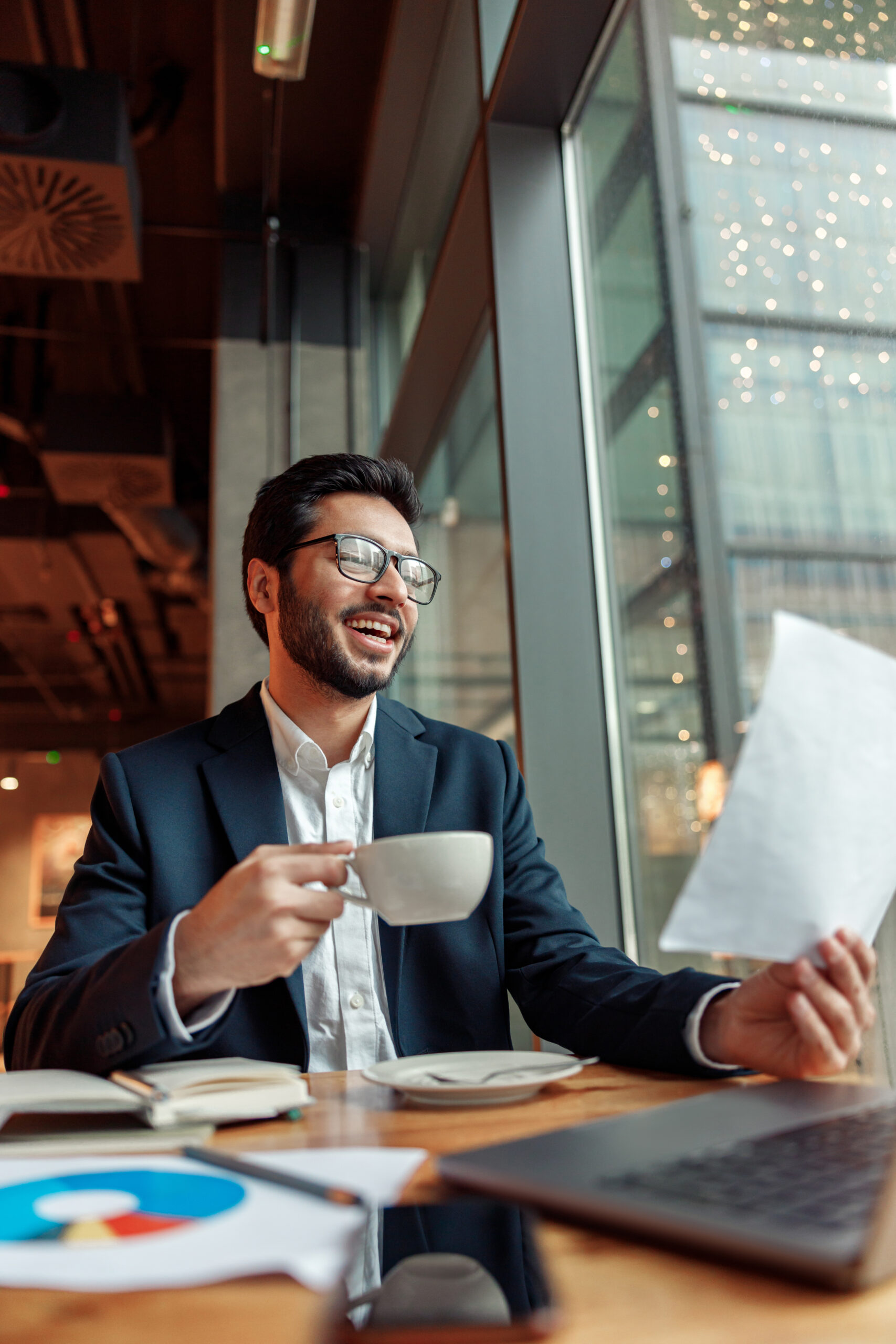 Positive indian businessman drinking coffee in cafe during working day. High quality photo